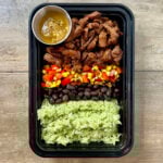 Honey Lime Steak Burrito Bowls in black meal prep container.